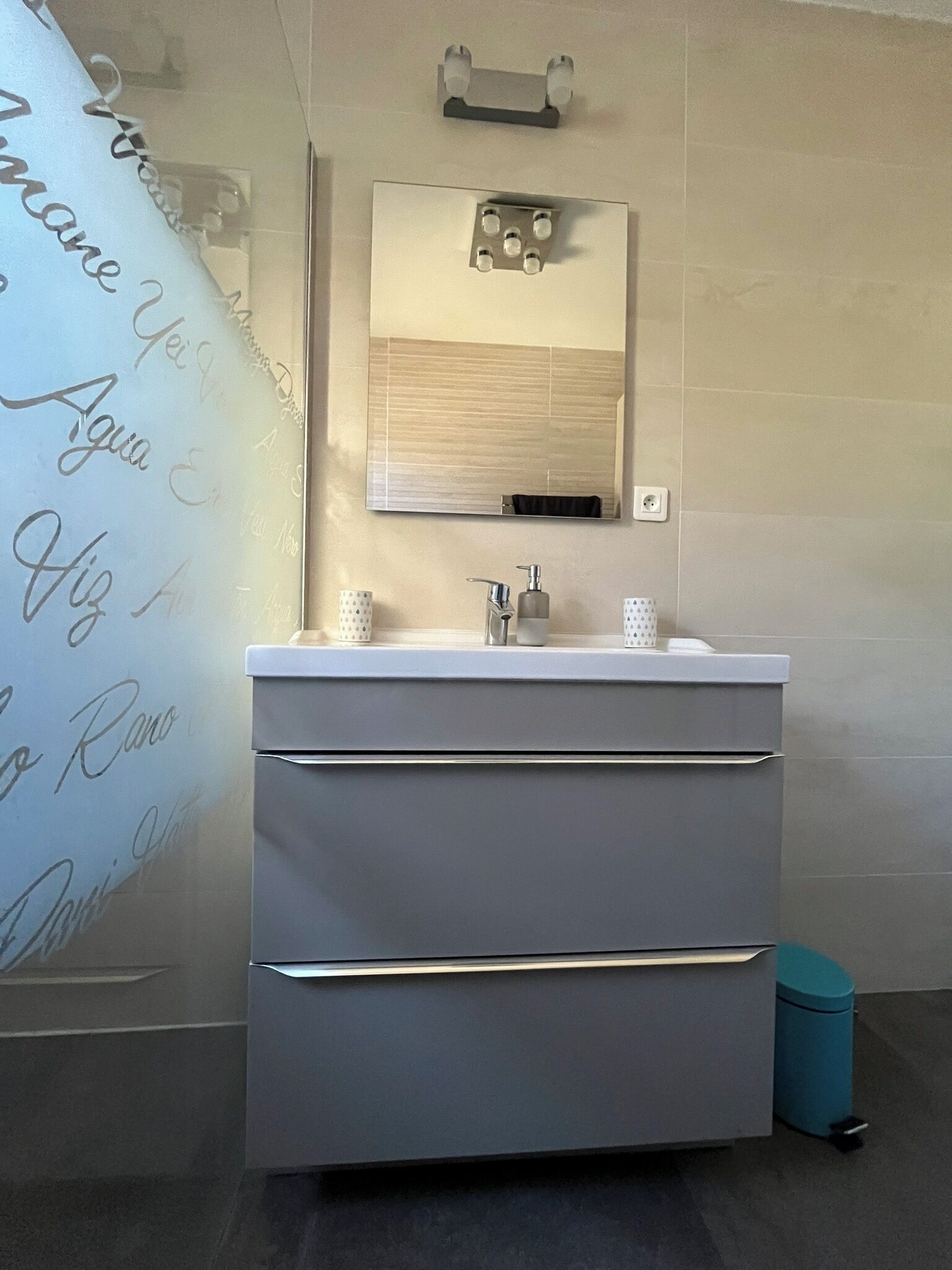 A modern bathroom with a white vanity, a mirror, and a towel rack.