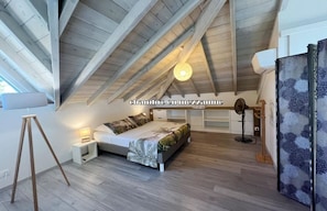 Cozy loft-style bedroom with a sloped ceiling, featuring a comfortable bed and ample natural light.