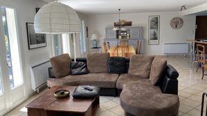 A living room with a sectional sofa, a wooden coffee table, a pendant light, a fireplace, and a dining area with a table and chairs. - Large contemporary house with garden (Seillons-Source-d'Argens)