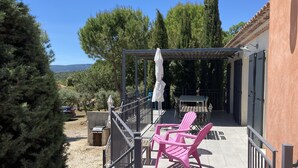 A patio with a table and chairs, a covered seating area, and a view of trees and mountains. - Large contemporary house with garden (Seillons-Source-d'Argens)