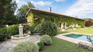 Une maison avec une piscine, entourée d’un jardin bien entretenu et d’un chemin en pierre.