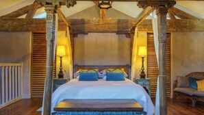 Un dormitorio con una cama grande, vigas de madera y un banco.