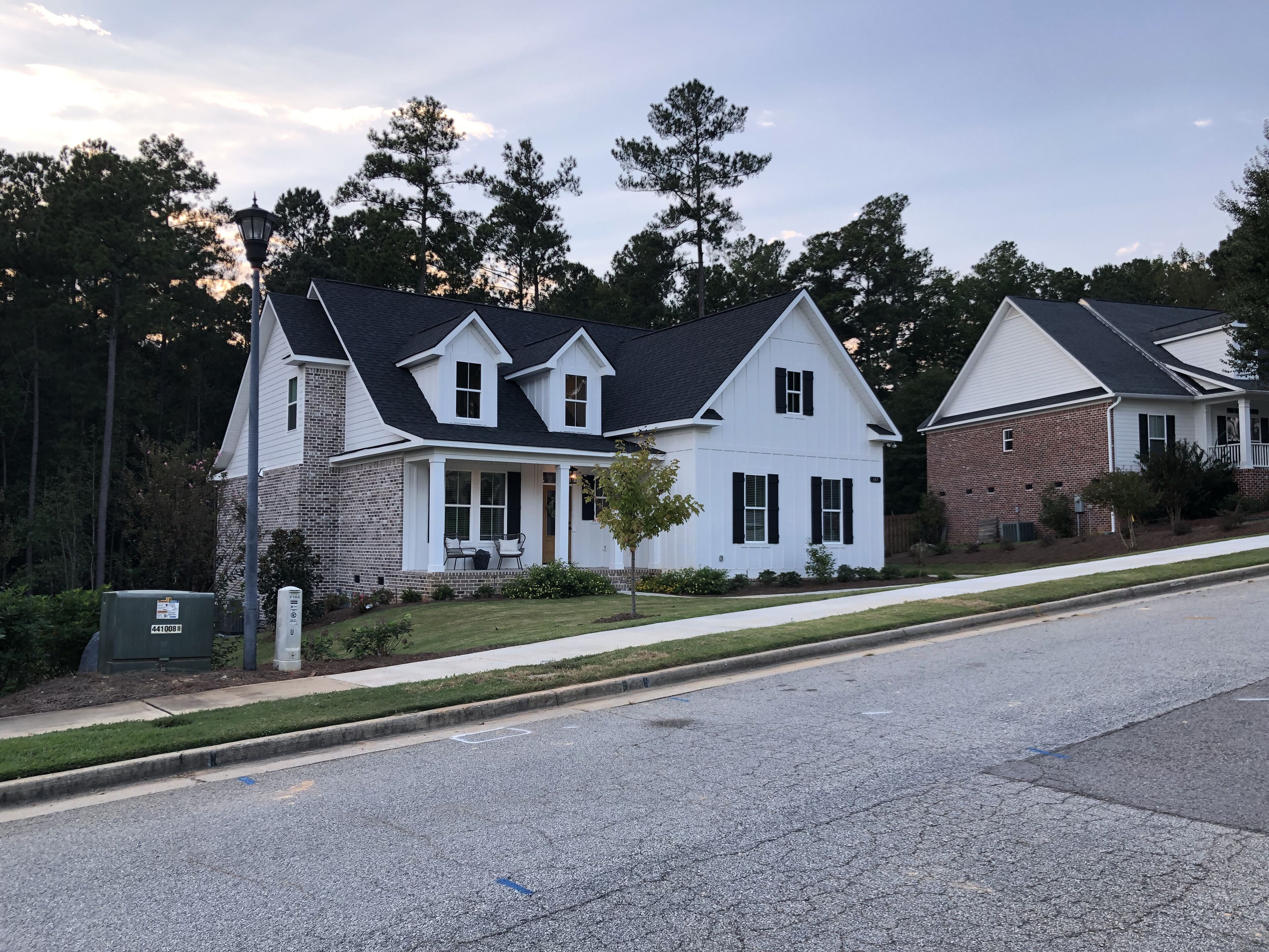 A residential street with houses featuring gabled roofs and front porches.