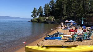 Ein Strand mit Kajaks, einem Rettungsturm und blauem Himmel.