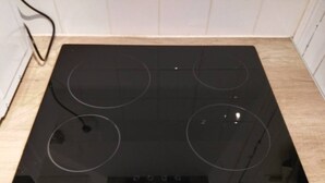 A black induction cooktop with four burners and a control panel. - Comfy Parisian studio! (Ivry-sur-Seine)