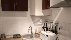 A compact kitchen with a washing machine, microwave, sink, and stove. - Comfy Parisian studio! (Ivry-sur-Seine)