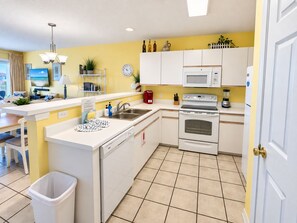 A compact kitchen with white cabinets, a microwave, an oven, and a sink.