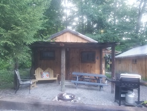 Una cabaña de madera con una mesa de picnic y una parrilla.