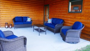 Een blokhut met twee blauwe gestoffeerde banken, een rieten stoel en een kleine tafel.