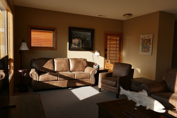 A living room with a brown leather sofa, a wooden coffee table, and a lamp.