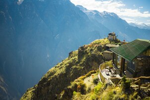 Un refugio de montaña con terraza y vistas a las montañas circundantes.
