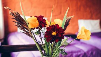 Eine Vase mit Blumen auf einem Tisch in einem Zimmer mit einem Bett und einem Poster an der Wand.