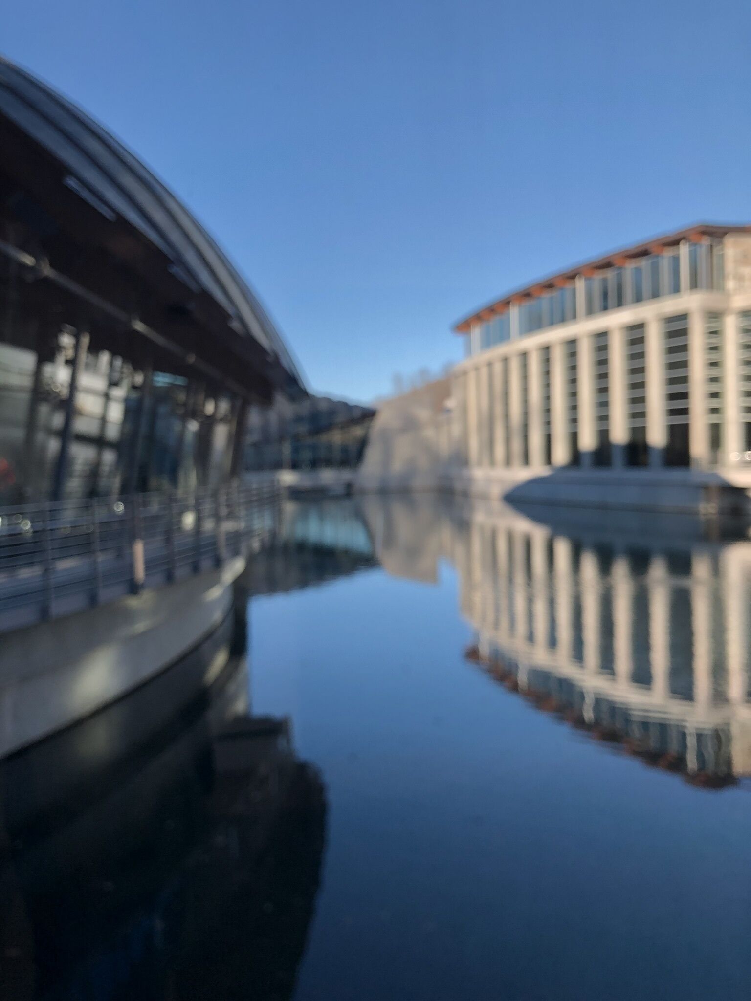 Un edificio moderno con fachada de vidrio que se refleja en el agua.