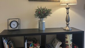 A bookshelf with books, a clock, a vase with flowers, and a lamp. - Work & Play in our High Country Hideaway (Boone)