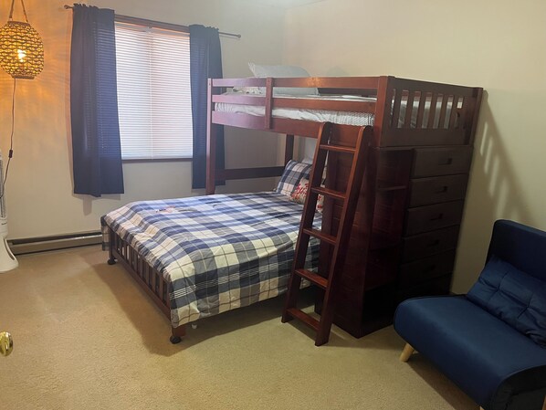 A bedroom with a bunk bed, a desk, a chair, a lamp, and a window with blinds. - Work & Play in our High Country Hideaway (Boone)
