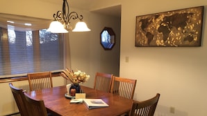 A dining room with a wooden table, six chairs, a vase with flowers, and a world map on the wall. - Work & Play in our High Country Hideaway (Boone)