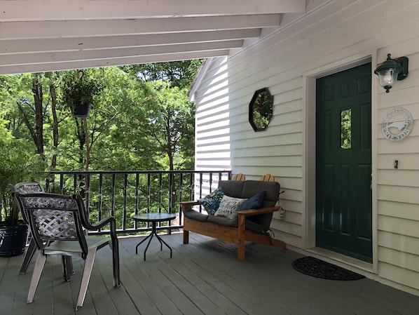Relax on the covered porch with a comfortable wooden rocker and a metal chair, perfect for taking in the surroundings.