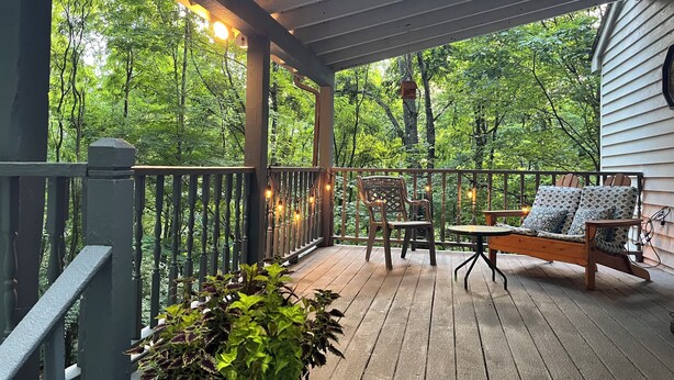 A covered porch with a wooden deck, a table with chairs, and a hanging light fixture. - Work & Play in our High Country Hideaway (Boone)