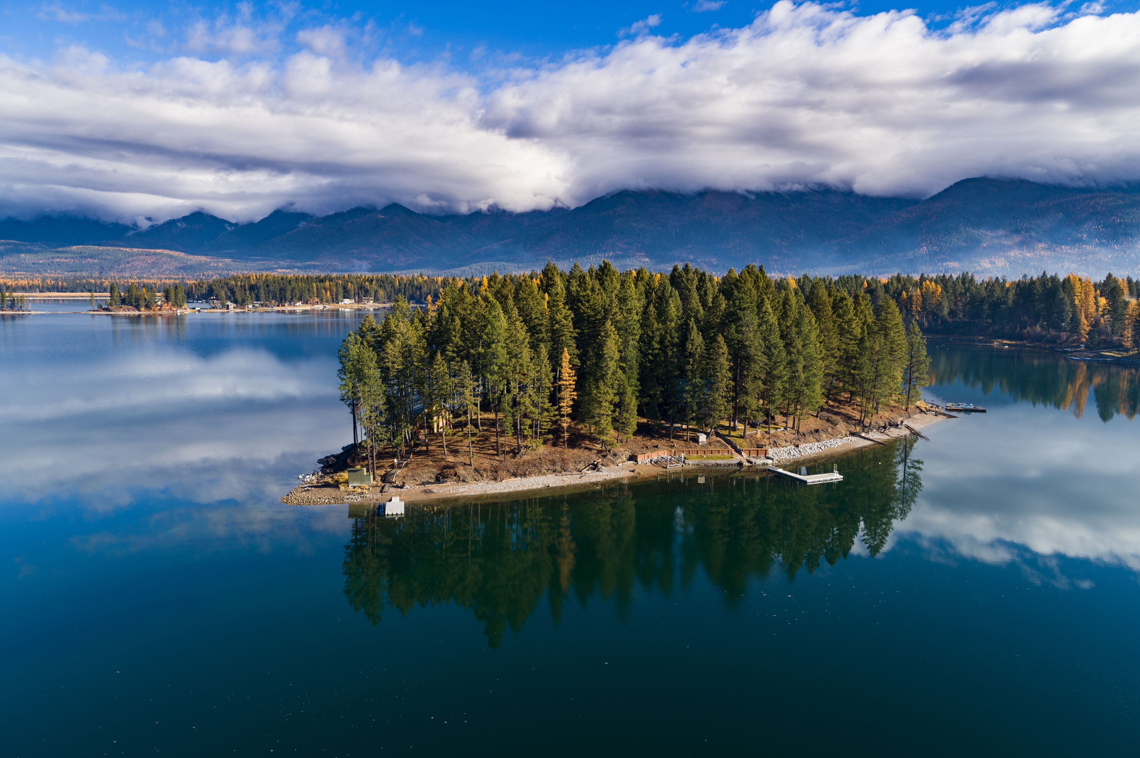 A serene lake with a small island featuring dense trees and a dock.