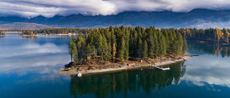 A serene lake with a small island featuring dense trees and a dock.