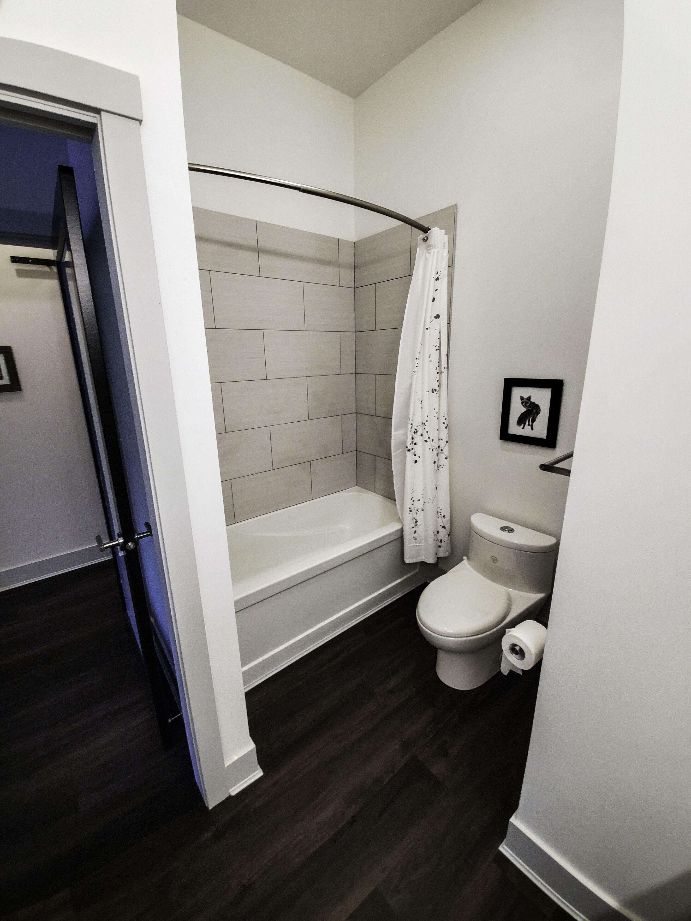 Une salle de bain avec une douche, des toilettes et un tableau encadré au mur.