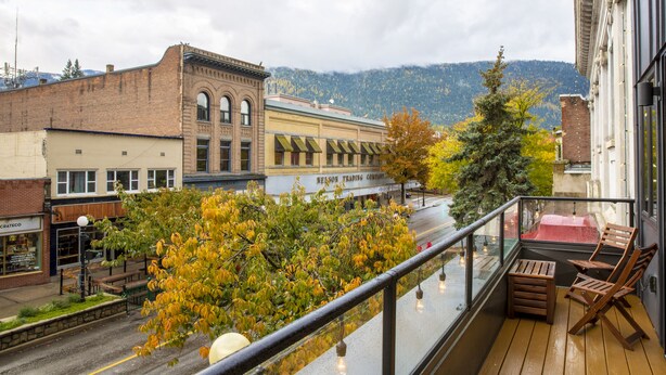 Ein Balkon mit Blick auf eine Stadtstraße, ein Gebäude mit dem Schild 'Mason Trading Company' und Herbstlaub.