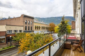 Un balcon donnant sur une rue de la ville, un bâtiment portant l’enseigne « Mason Trading Company », et le feuillage automnal.