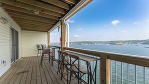 Una terraza de madera con mobiliario exterior y vista a un lago.