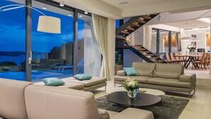 A modern living room with a large window, a staircase, and a dining area. - Beautiful professionally managed villa, walking distance to the Hvar City center (hvar)
