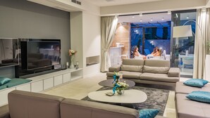 A modern living room with a flat-screen TV, sofas, a coffee table, and a glass door leading to a balcony with outdoor seating. - Beautiful professionally managed villa, walking distance to the Hvar City center (hvar)