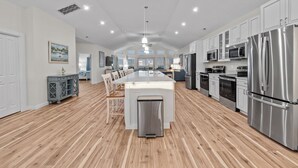 Una cocina amplia con una isla central, electrodomésticos de acero inoxidable y piso de madera.