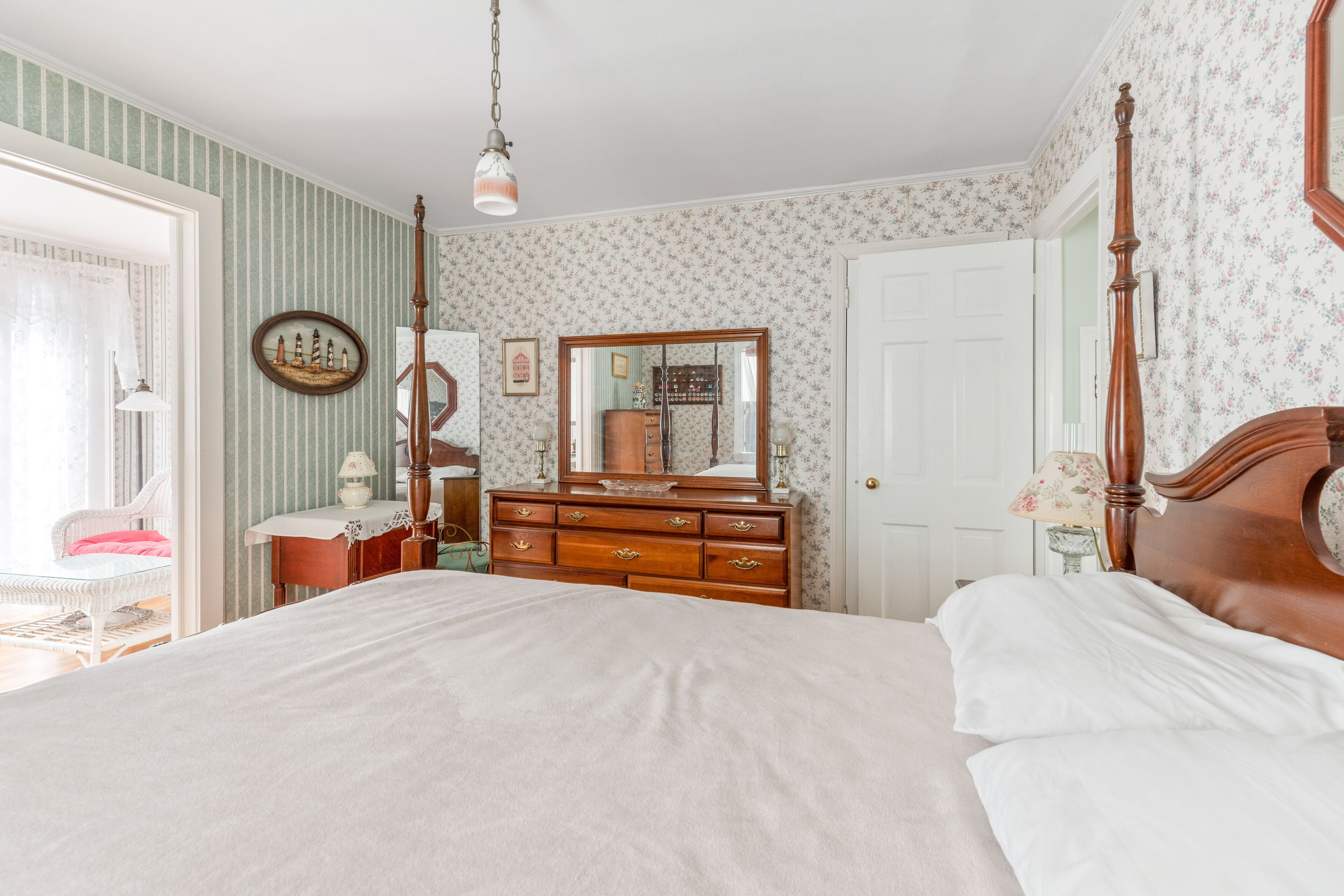 Une chambre à coucher avec un grand lit, une commode avec un miroir et une chaise.