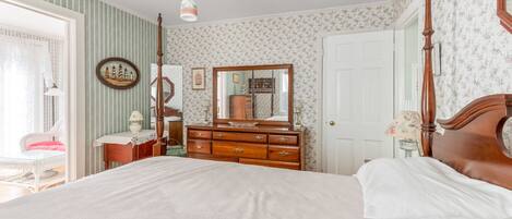 Une chambre à coucher avec un grand lit, une commode avec un miroir et une chaise.