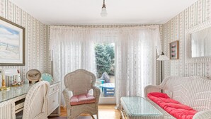 A room with wicker furniture, a glass table, and a red sofa.
