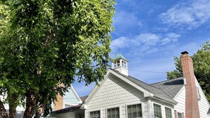 A white house with a brick chimney, a porch with flower boxes, and a well-maintained lawn.