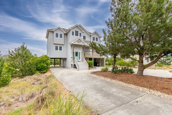 A two-story house with a front porch, a staircase leading to the entrance, and a driveway.