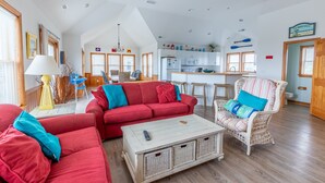 Ein geräumiges Wohnzimmer mit einem roten Sofa, einem Korbstuhl und einem Couchtisch.