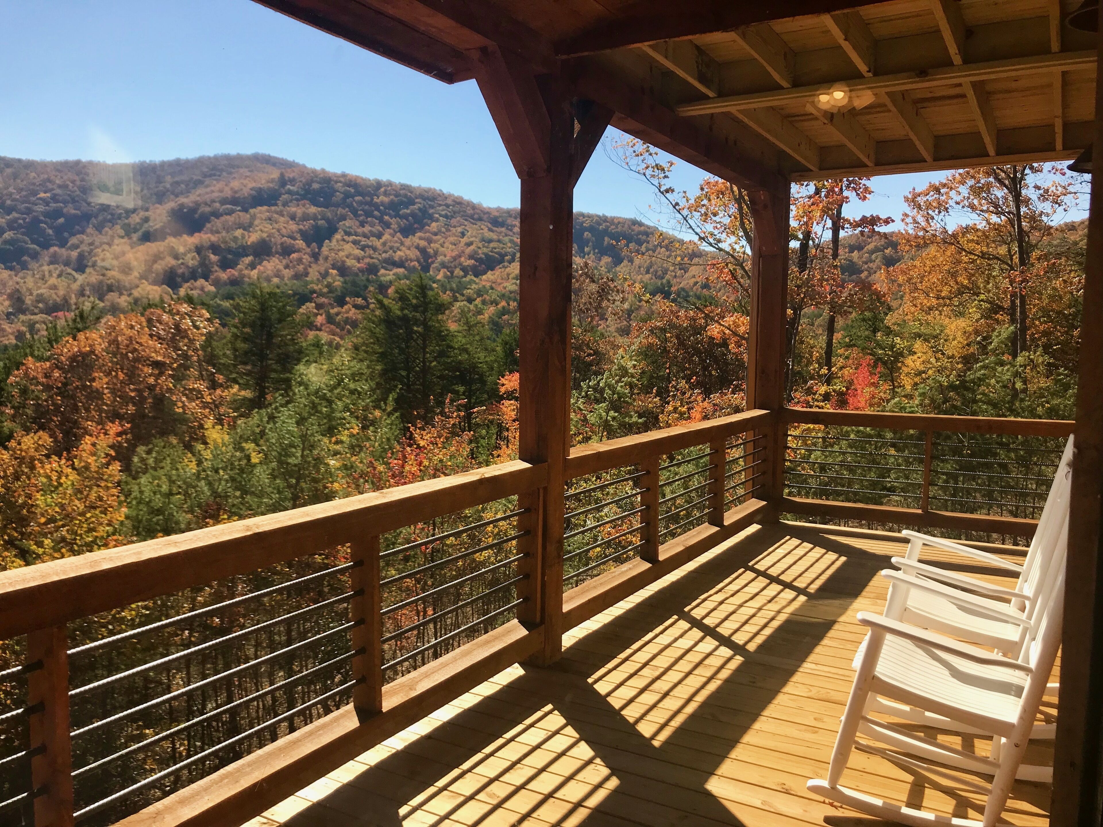 A wooden deck with a railing overlooking a forested hillside.