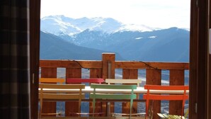 Un pontile in legno con sedie colorate affacciato su montagne innevate.