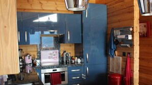 Una cucina compatta con mobili blu, un lavello in acciaio inossidabile e un cestino dei rifiuti rosso.