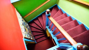 A spiral staircase with red carpeted steps and blue handrails. - Portree Independent Hostel (Portree)