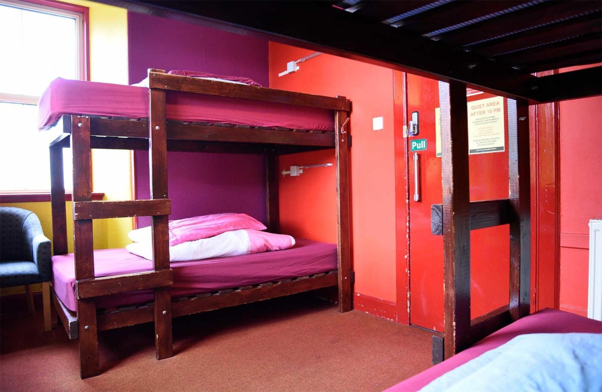 A bunk bed room with a pull door and a sign indicating a quiet area after 10 PM.
