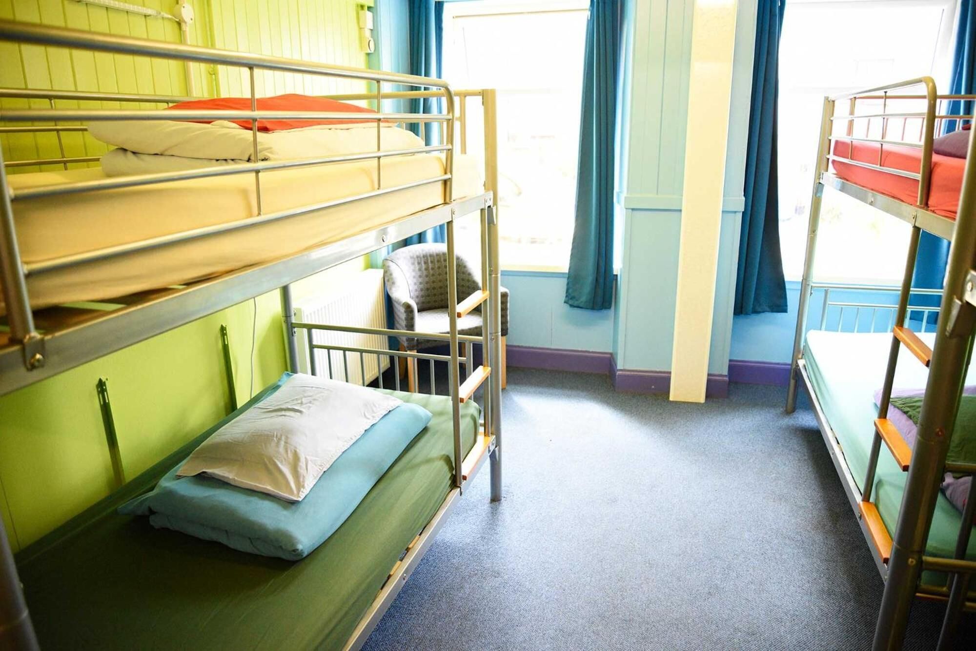 A bunk bed room with a chair and a window with curtains.