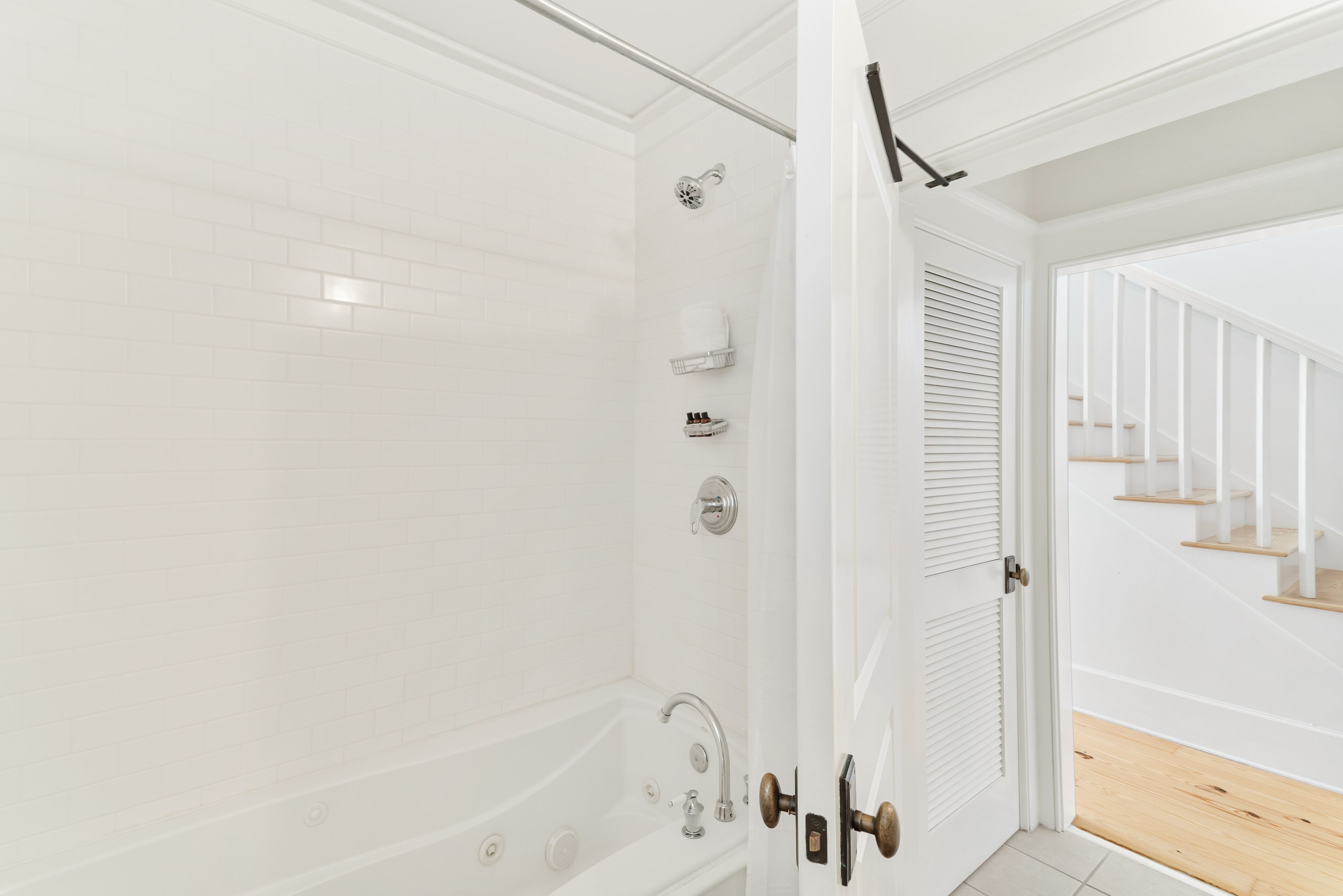 Une salle de bain moderne avec une douche à l’italienne, une baignoire et un mur recouvert de carreaux blancs.