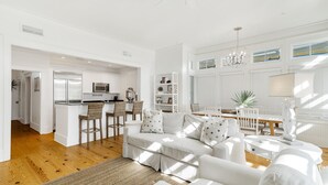 A modern kitchen with white cabinetry, a stainless steel refrigerator, and a bar area with stools. - Beach days made better under the brim at Beach Hat/ Gulf Views / 2 Bikes (WaterColor)