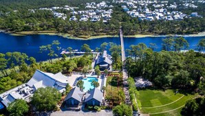 An aerial view of a resort with a swimming pool, tennis court, and a dock extending into a lake. - Beach days made better under the brim at Beach Hat/ Gulf Views / 2 Bikes (WaterColor)