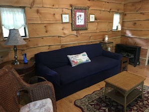 Una sala de estar acogedora con un sofá azul, una mesita, una silla de mimbre y una chimenea.