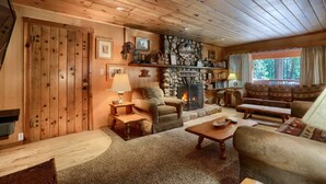 A cozy cabin interior with a fireplace, wooden walls, and a comfortable seating area.