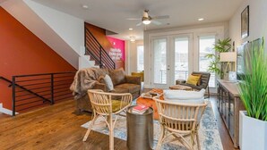Un salon moderne avec un escalier, un ventilateur de plafond et une grande fenêtre.