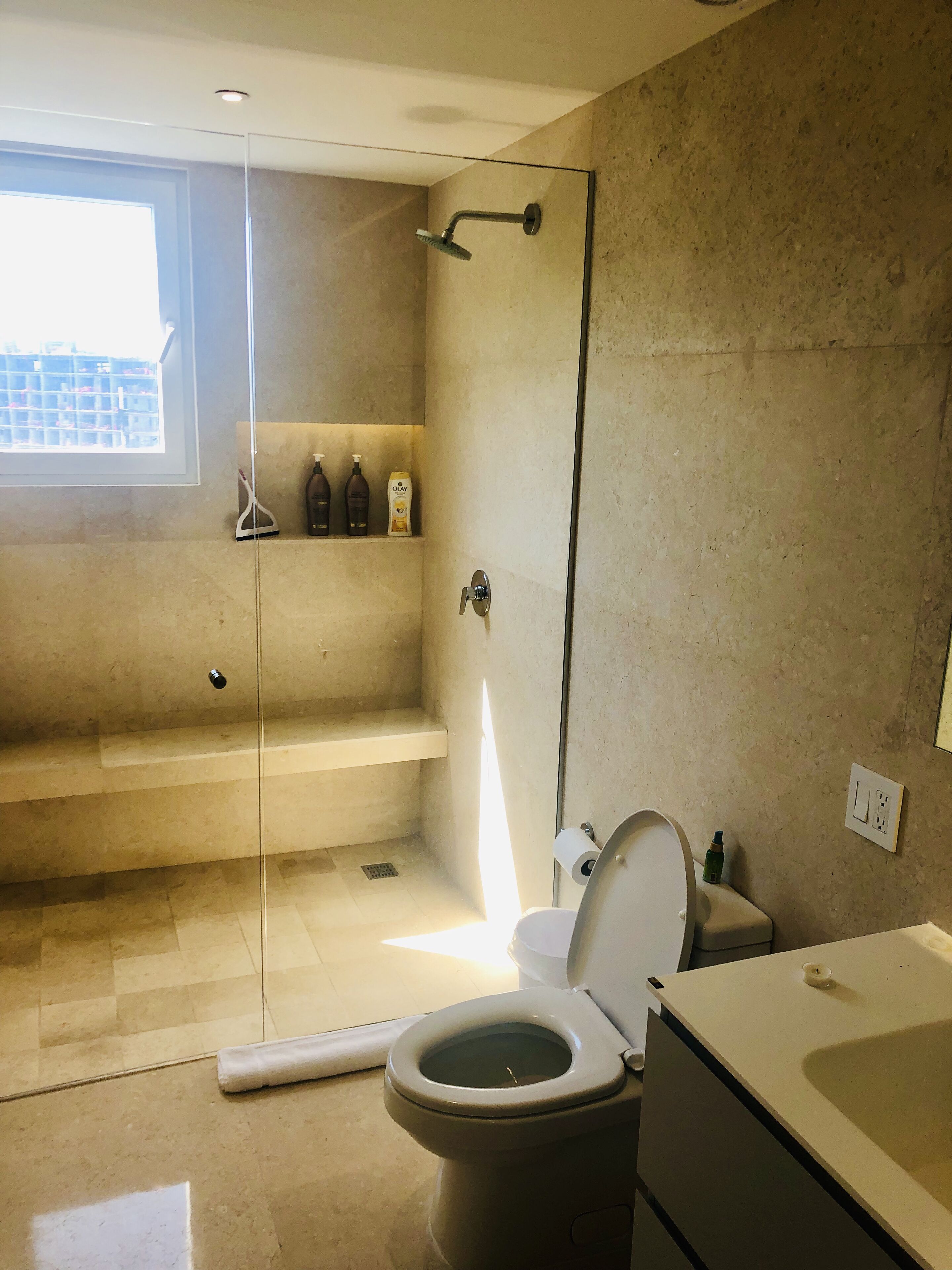 Uma casa de banho moderna com cabine de duche em vidro, sanita e lavatório.